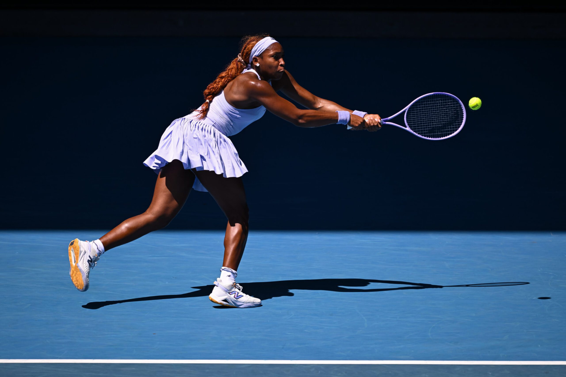 A tennis player returning the ball on a blue court