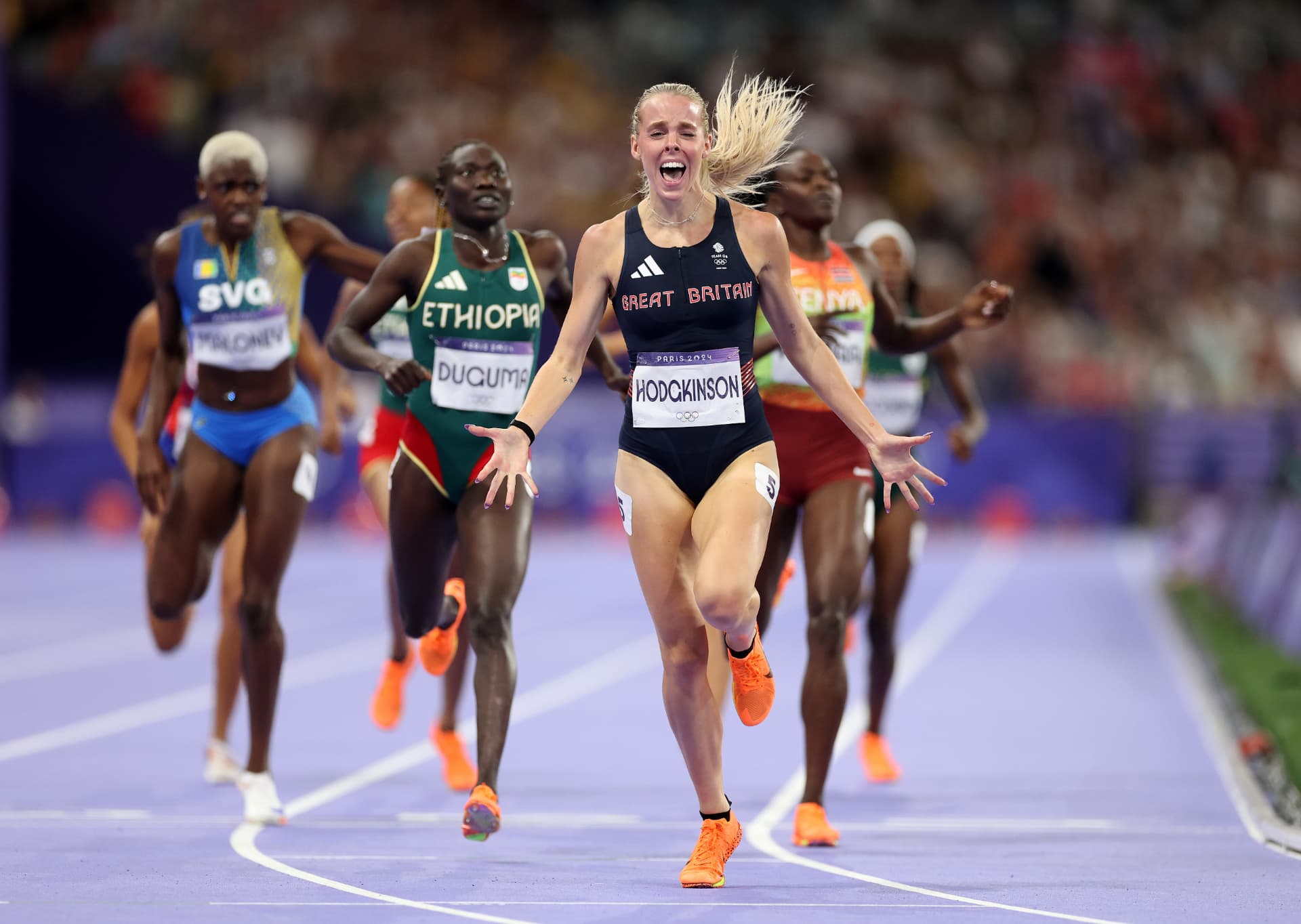 A track athlete celebrating as she crosses the finish line